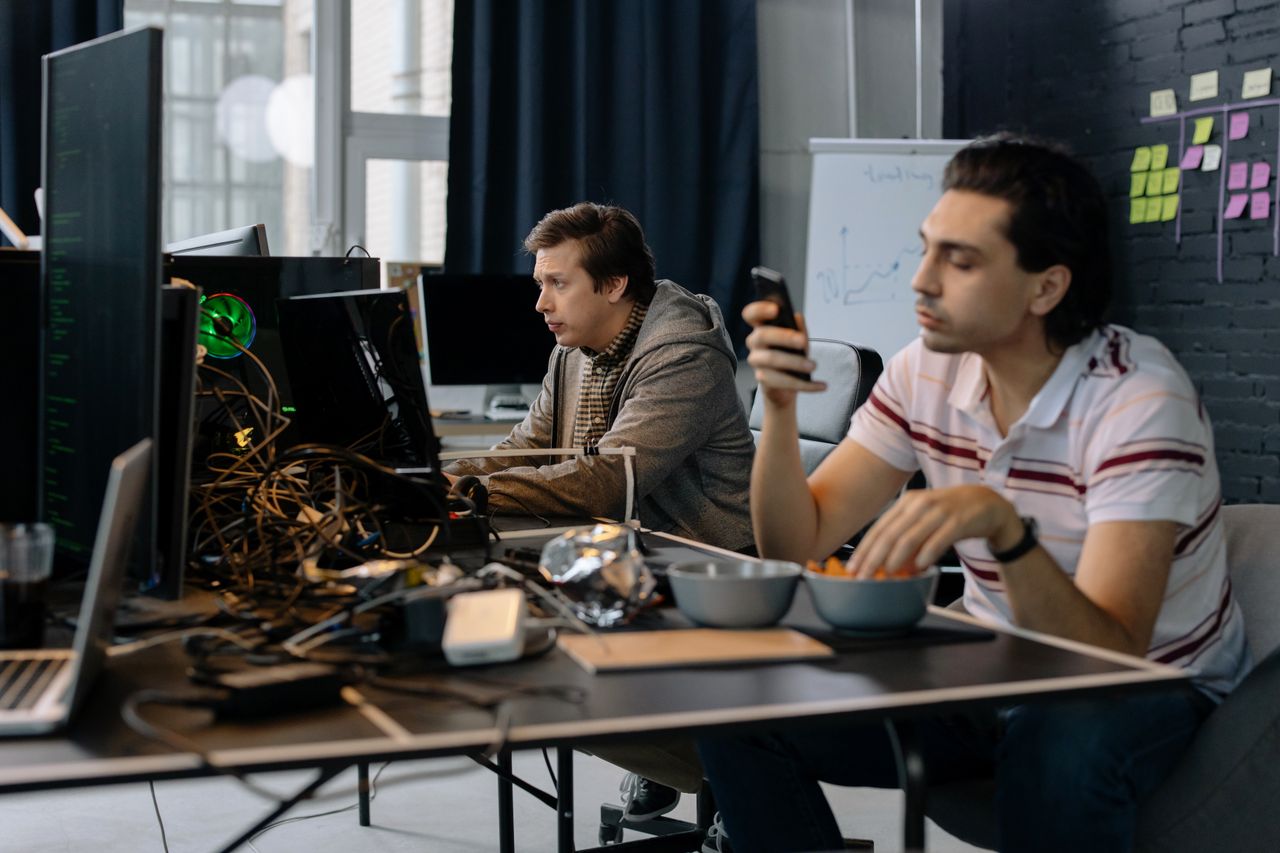 gallery-1 Two men working in a modern office setup, focused on technology and collaboration.